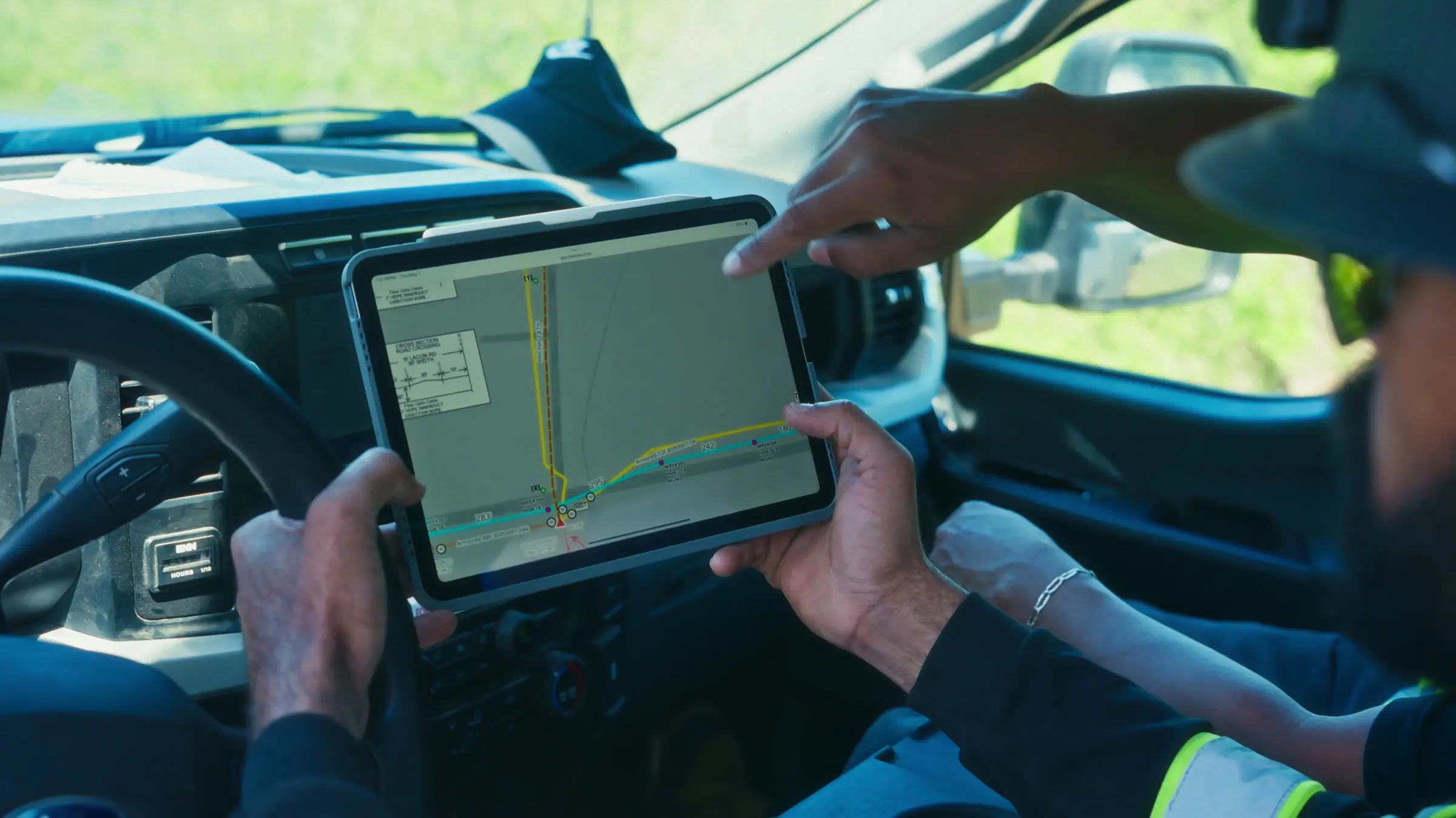 Crew reviewing the route map and redlines on a tablet inside the truck
